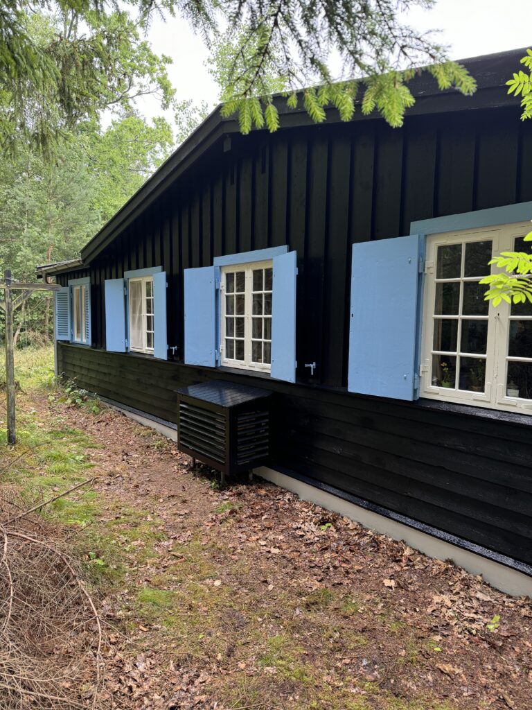 Sortmalet træfacade med lyseblå vinduesrammer efter udvendig maling